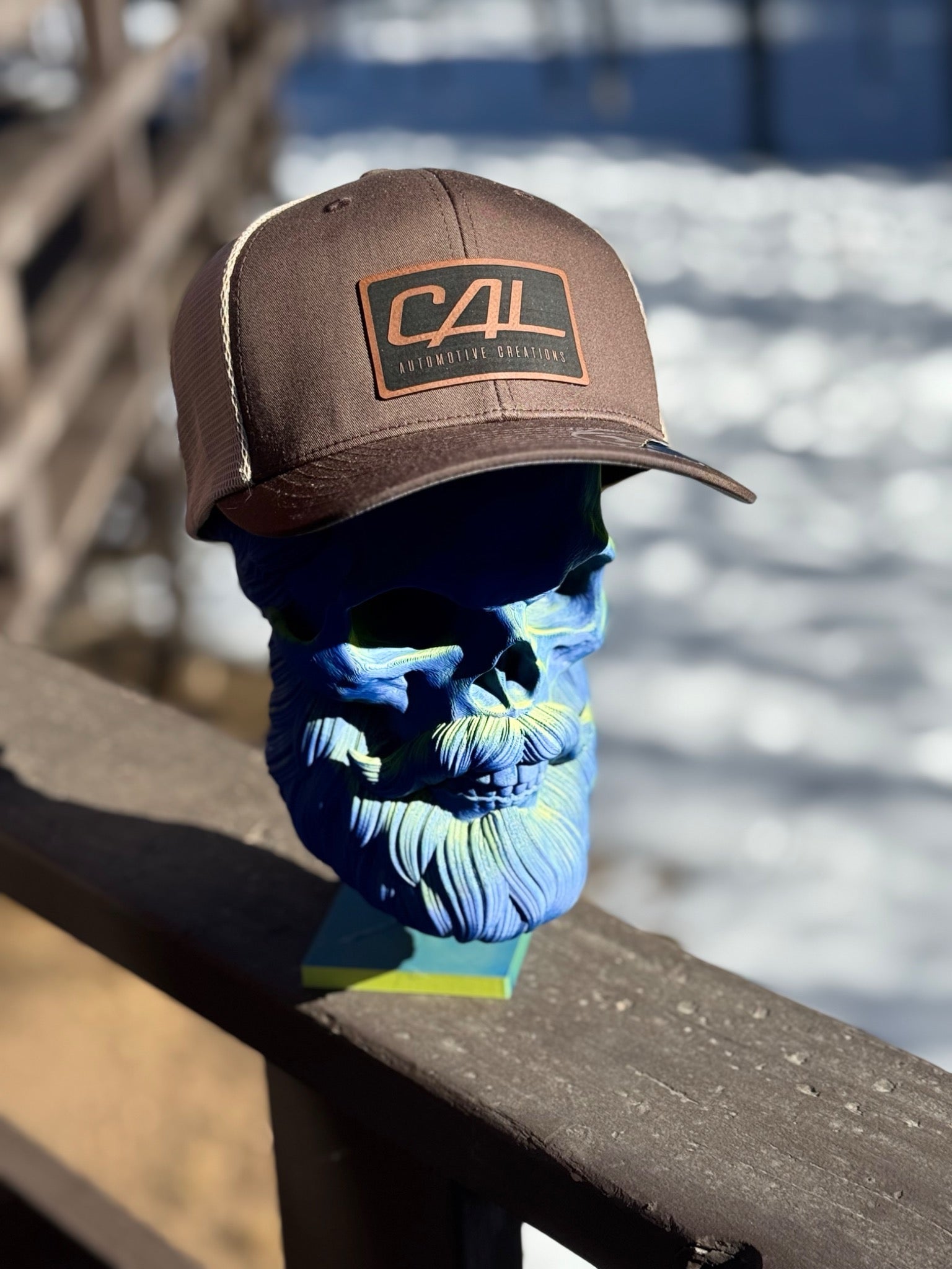 Blue face mask with a beard design worn by a person wearing a brown cap with 'CAL' logo.