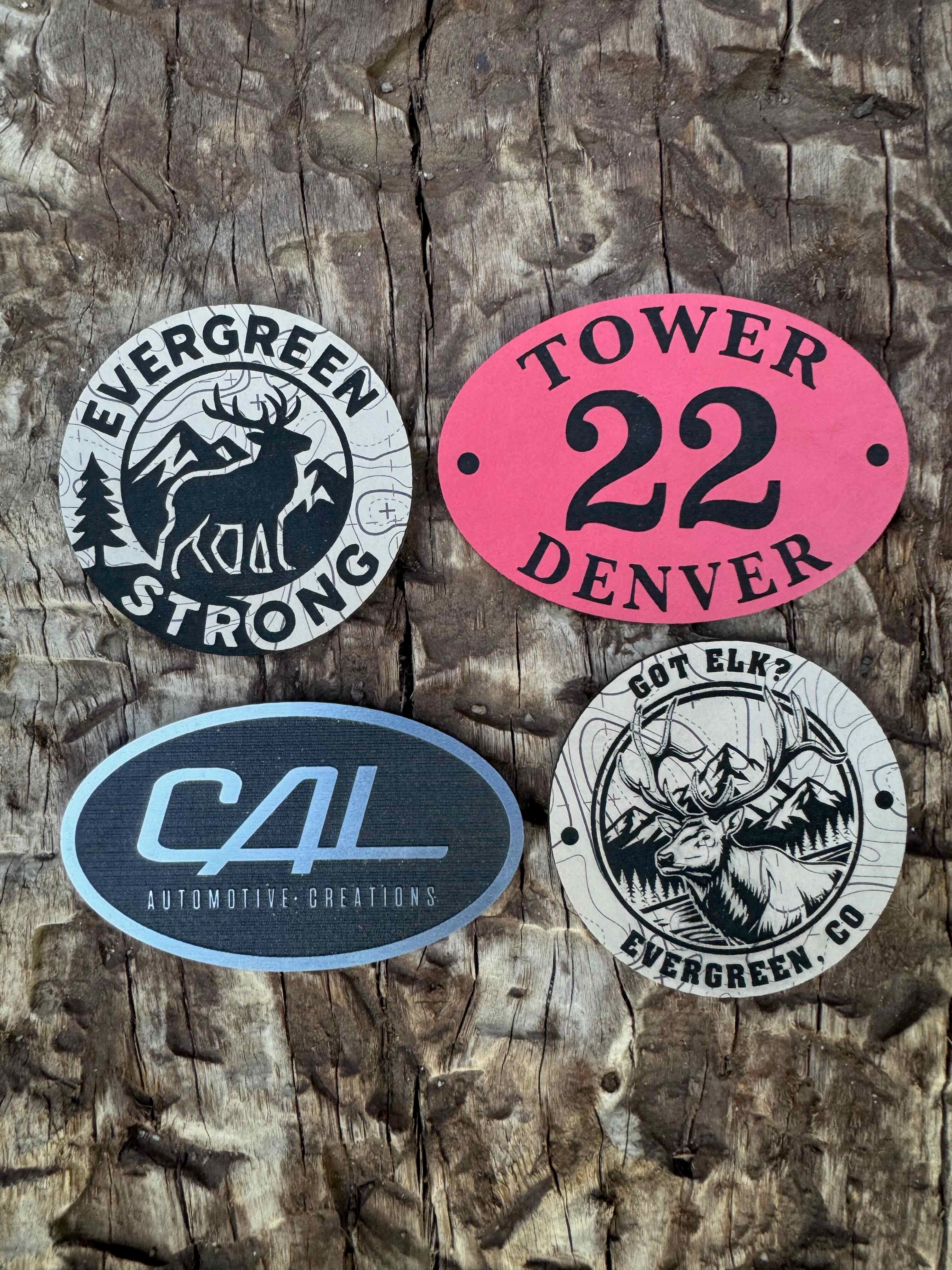 Four metal tags with different designs and text on a wooden surface