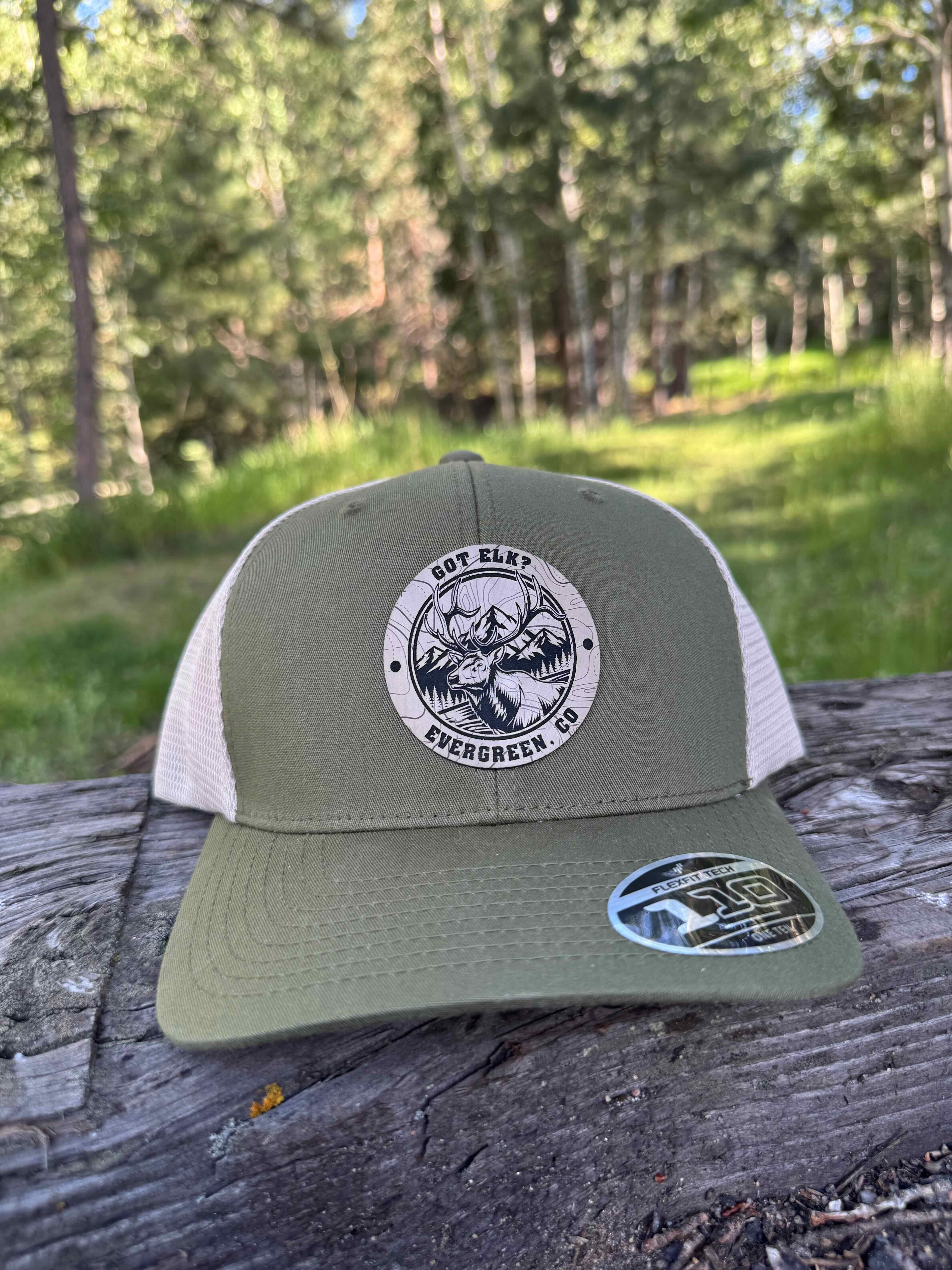 Green and beige cap with a logo on a wooden post outdoors