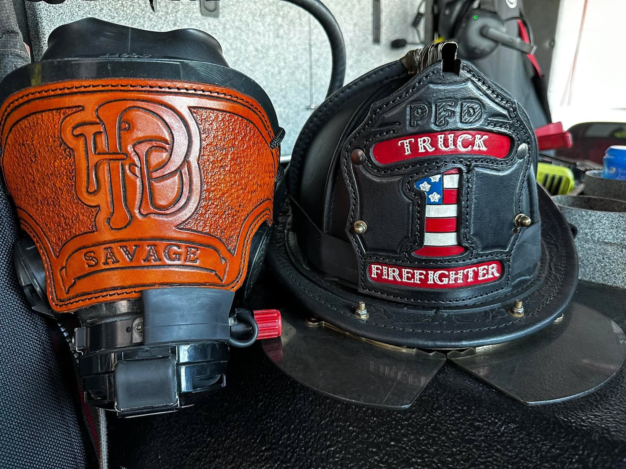 Firefighter helmet with 'PFD Truck Firefighter' patch and Savage gas mask on a dark surface.